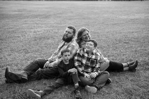 A series of black and white photos showing people playfully lying in grass and enjoying time together outdoors.