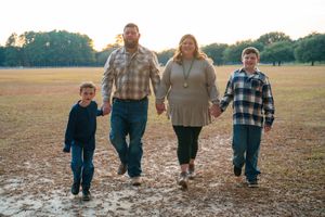 Family walking together through a muddy field during autumn season.