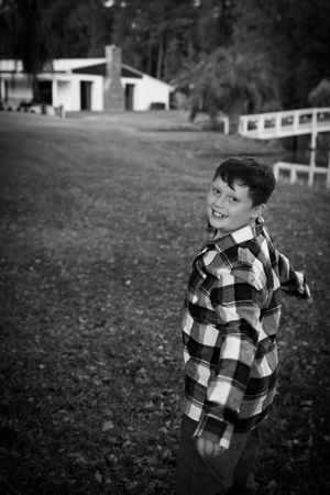 Black and white photo sequence of a child playing and jumping outdoors in a plaid shirt.