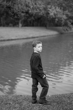 Black and white series showing a small figure walking along a grassy bank beside a lake.