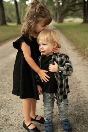Sweet interaction between two people on a gravel path surrounded by trees.