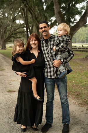 Happy family sharing playful moments together on a tree-lined path.