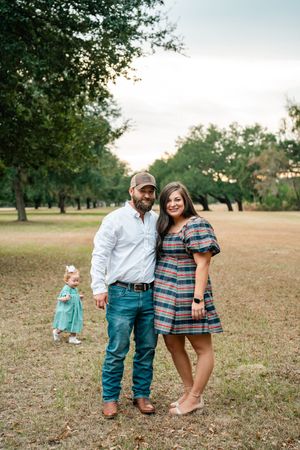 A series of candid family moments captured in a grassy field with trees during golden hour.