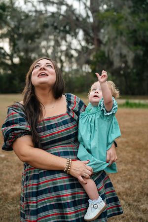 A joyful outdoor moment with matching plaid dresses against a backdrop of moss-draped trees.