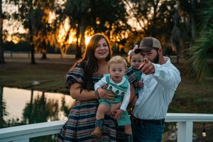 A sunset family portrait on a deck overlooking water with Spanish moss trees in the background.