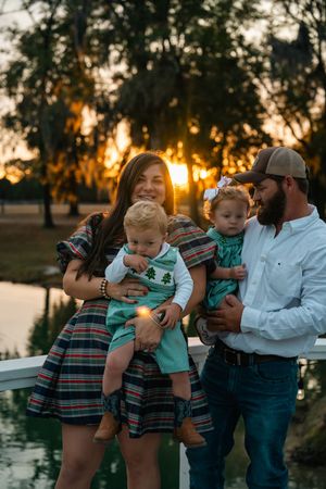 Sunset family photo series by a lake showing tender moments in matching casual outfits.