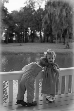 A sequence of black and white photos showing a child leaning over a white porch railing in different playful poses.