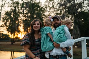 A family sits together on a dock at sunset wearing coordinating turquoise and casual outfits.