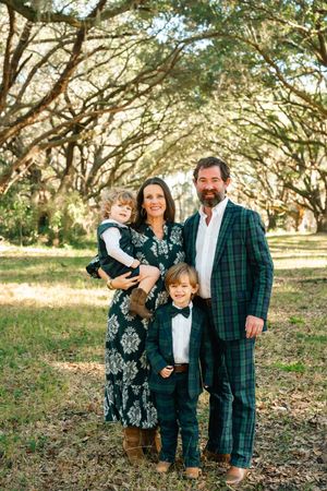 Family portrait session in a rustic outdoor setting with oak trees and natural lighting.