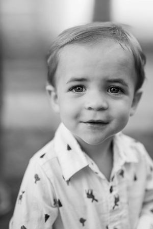 Black and white close-up portrait of a young child in a patterned shirt.
