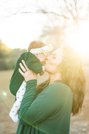 A romantic couple embraces in a sunlit outdoor setting with a dreamy golden glow and lens flare effect.