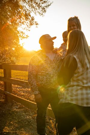 Candid family moment captured during sunset with golden light filtering through trees.