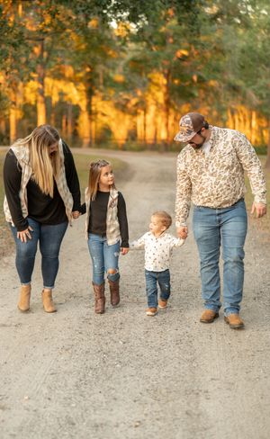 Family members walking together on gravel path during golden hour.