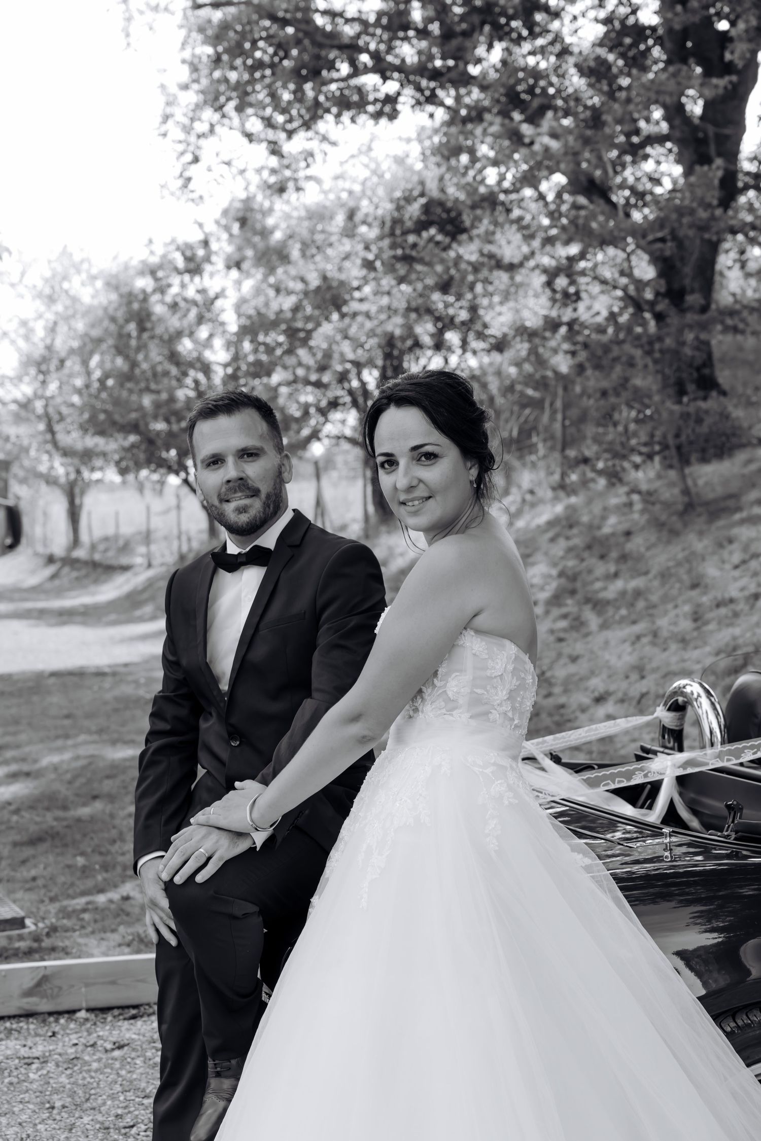 Romantic wedding couple poses on rustic wooden bench surrounded by autumn trees. Domaine la Plume photographe mariage