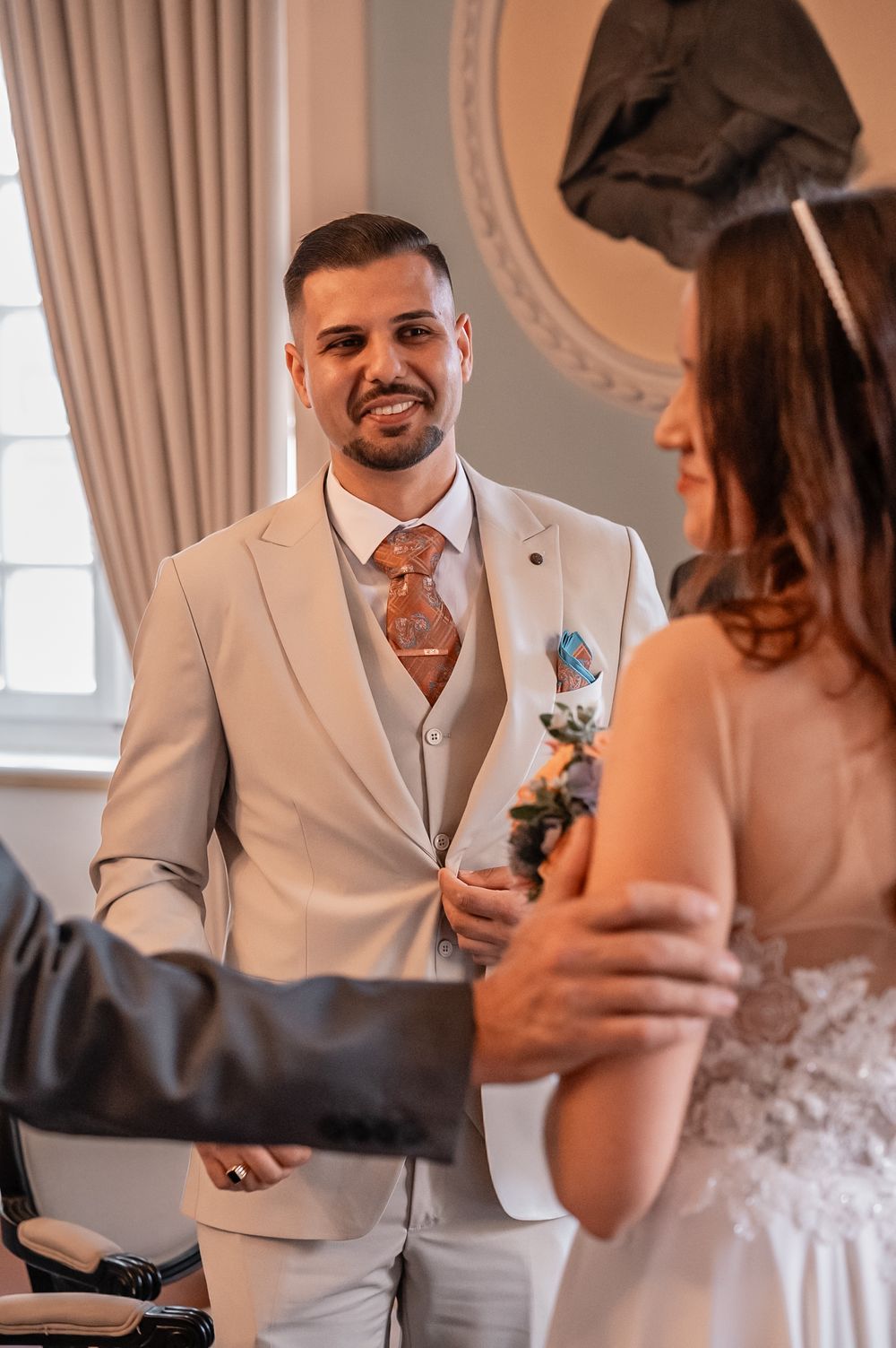 A couple shares an intimate first look moment at their wedding, with the groom in a light suit and boutonniere.