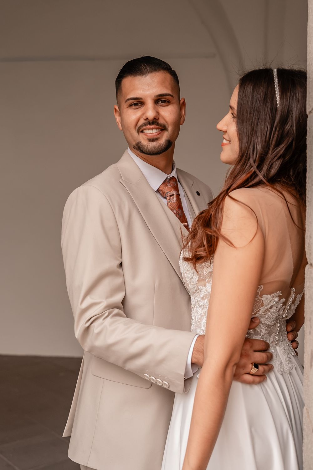 Intimate wedding couple portraits in beige and white attire against neutral background.