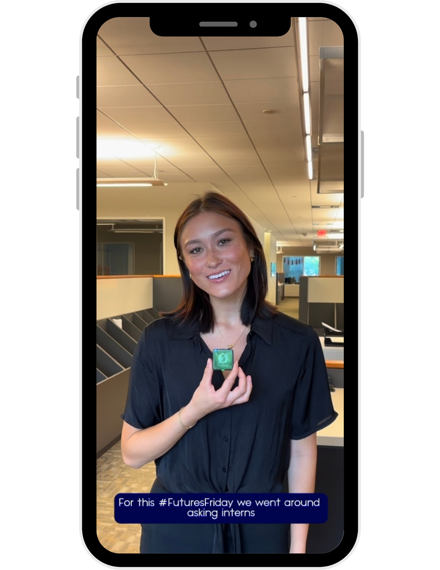 A person in a black shirt stands in an office space holding a small green object.