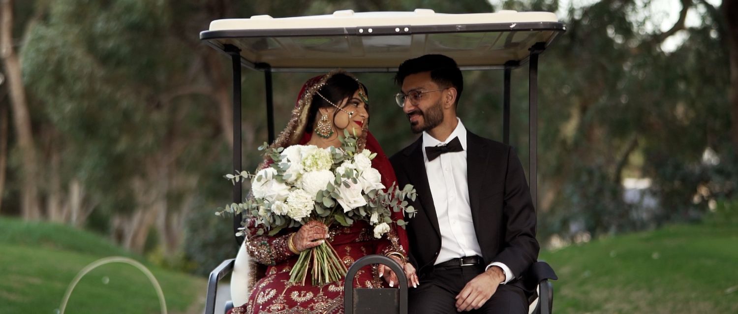 Couple sharing intimate moment under trees in formal wedding attire.