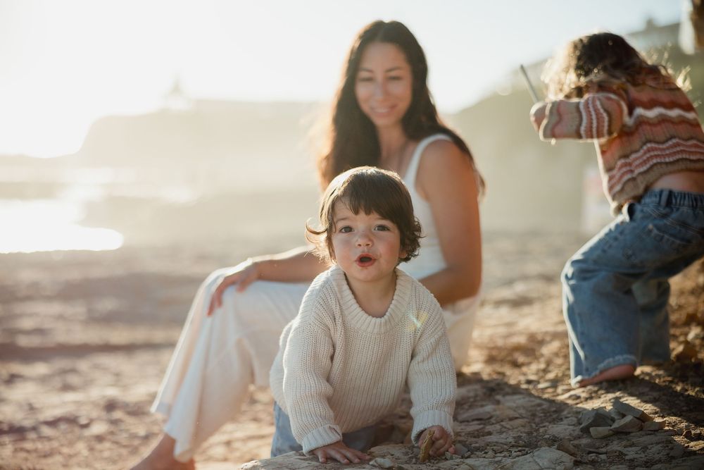 Family enjoying a golden sunset together on a beach during a warm summer evening.