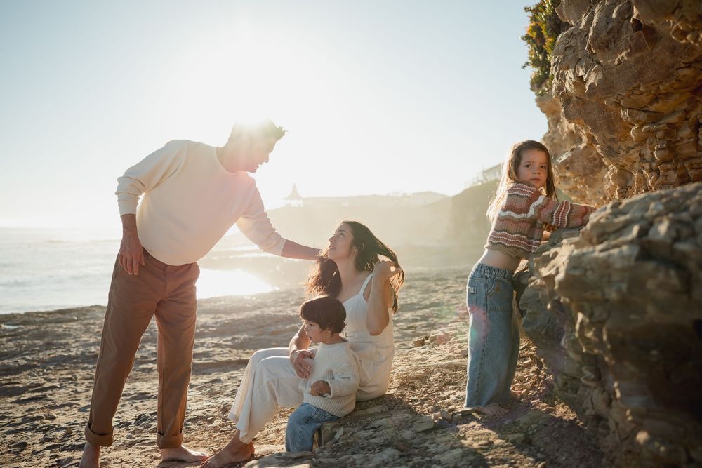 Family walking together on a scenic coastal beach path during golden hour sunset.