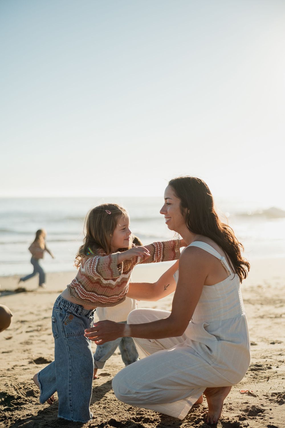 A heartwarming beach scene shows playful interactions between family members during golden hour.