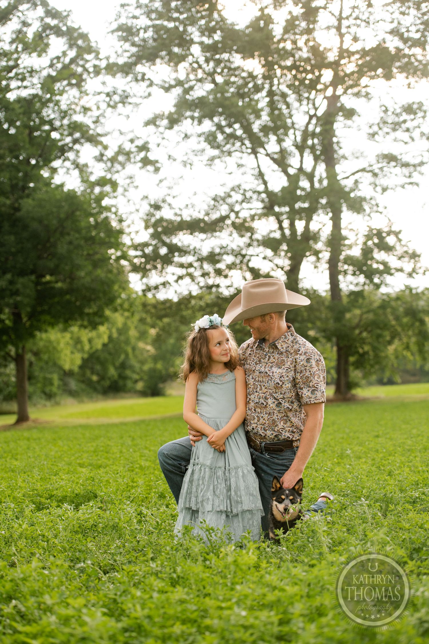 Intimate outdoor portrait in a lush field with western attire and soft evening lighting.