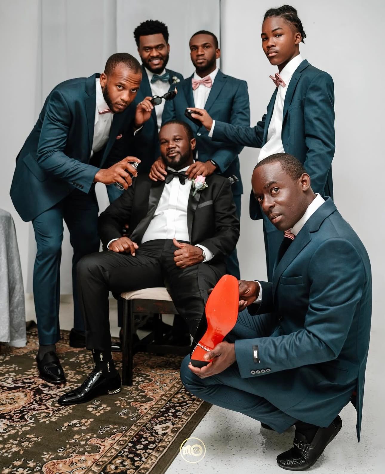 Groomsmen in navy suits share candid laughing moments during formal photo session.