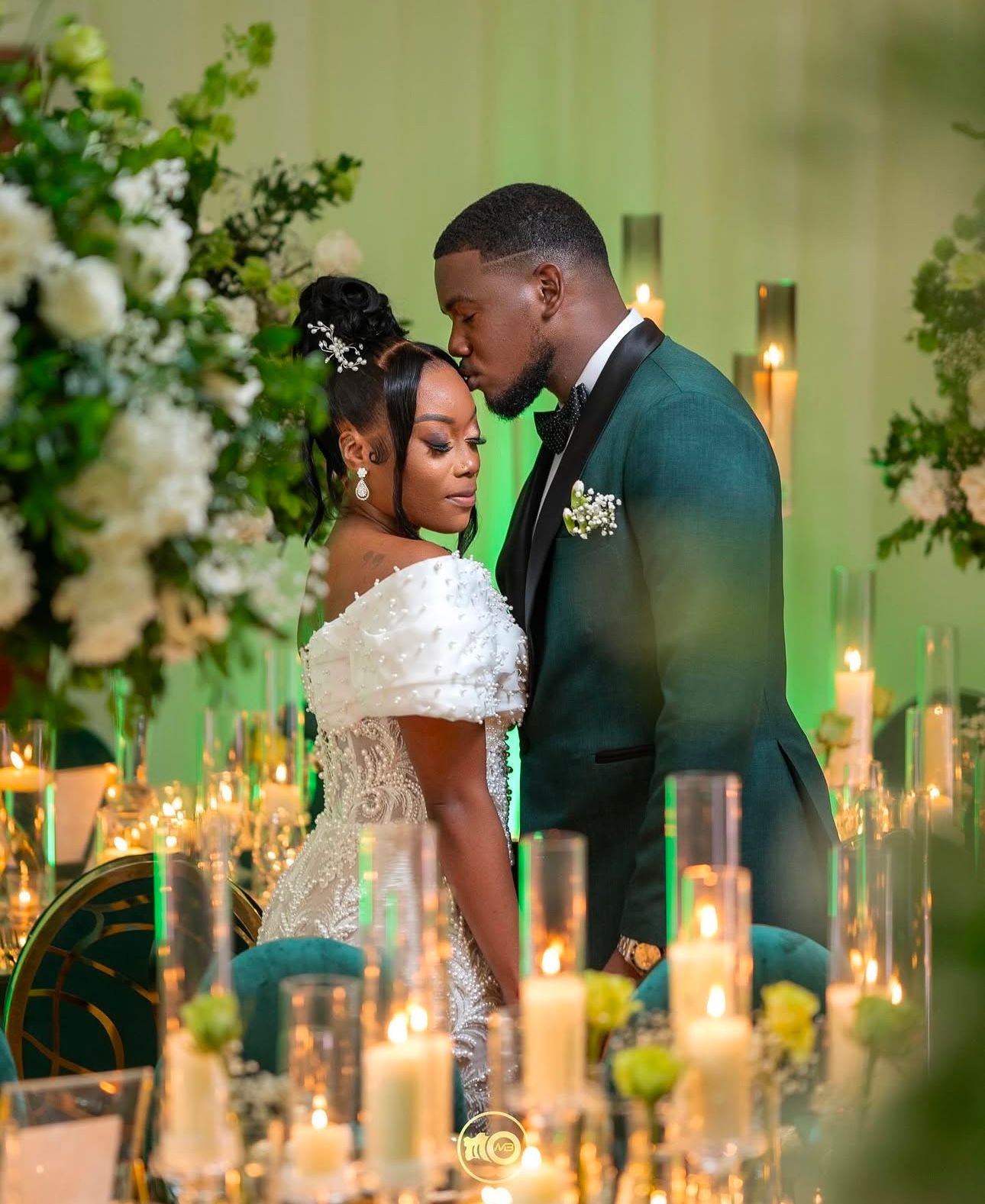 Romantic candlelit wedding reception setting with glowing candles and greenery decor.