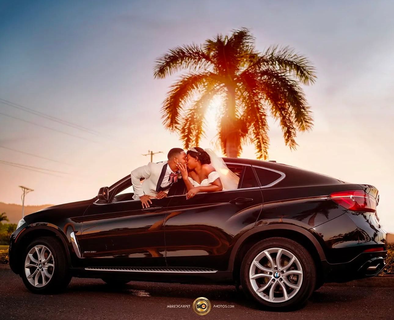 Luxury car photoshoot at sunset with palm trees silhouetted in background.
