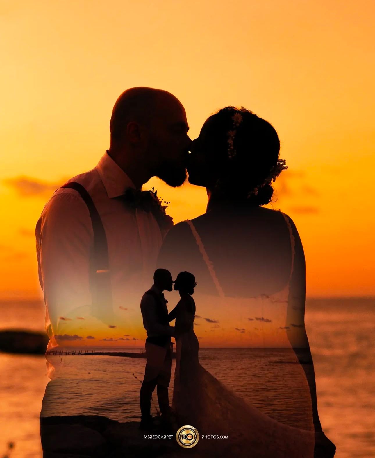 Silhouettes of couple against vibrant orange sunset over ocean.
