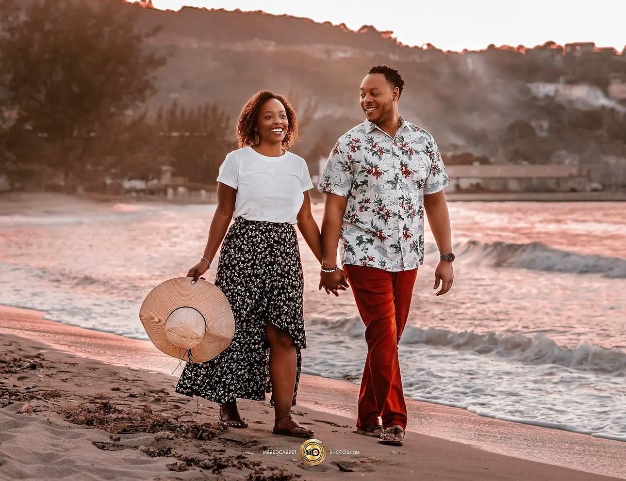 Couple walks along beach at sunset in casual attire.