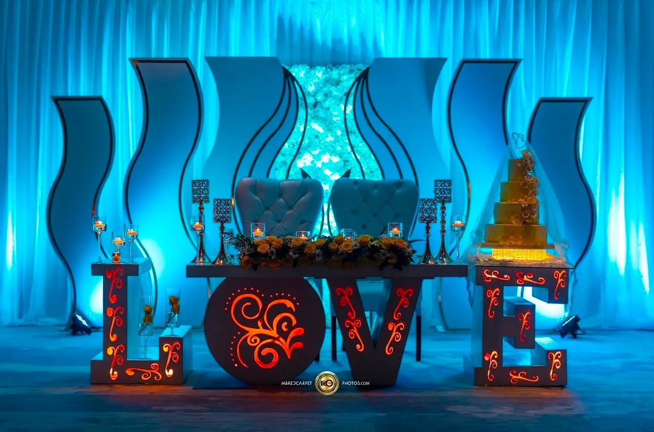 Reception venue decorated with dramatic blue uplighting and Moroccan-inspired lanterns.