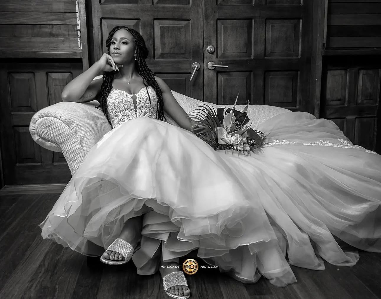 Elegant bride in white gown posing dramatically on vintage furniture.
