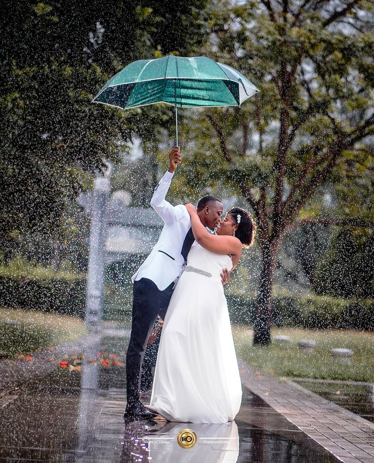 Couple shares romantic moment under turquoise umbrella in the rain.