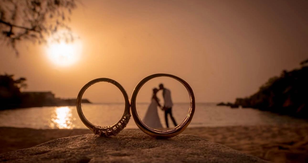 A series of silhouetted rings against a warm sunset sky over a calm ocean horizon.