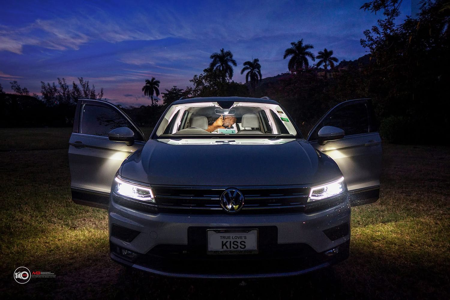 Sleek modern car with illuminated LED headlights photographed at dusk against a palm tree silhouetted backdrop.