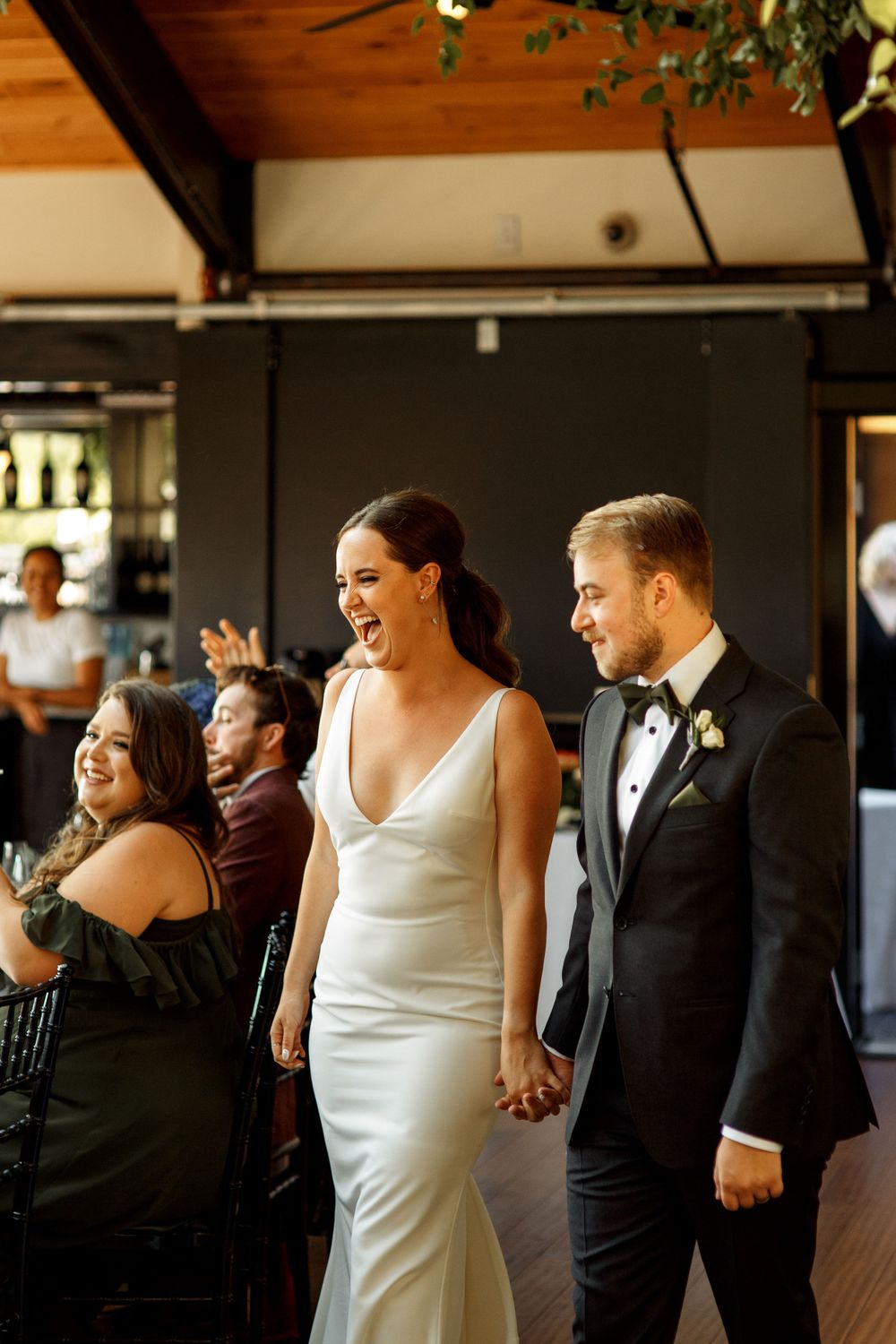 Wedding celebration with couple walking together in elegant white dress and black tuxedo at indoor venue.