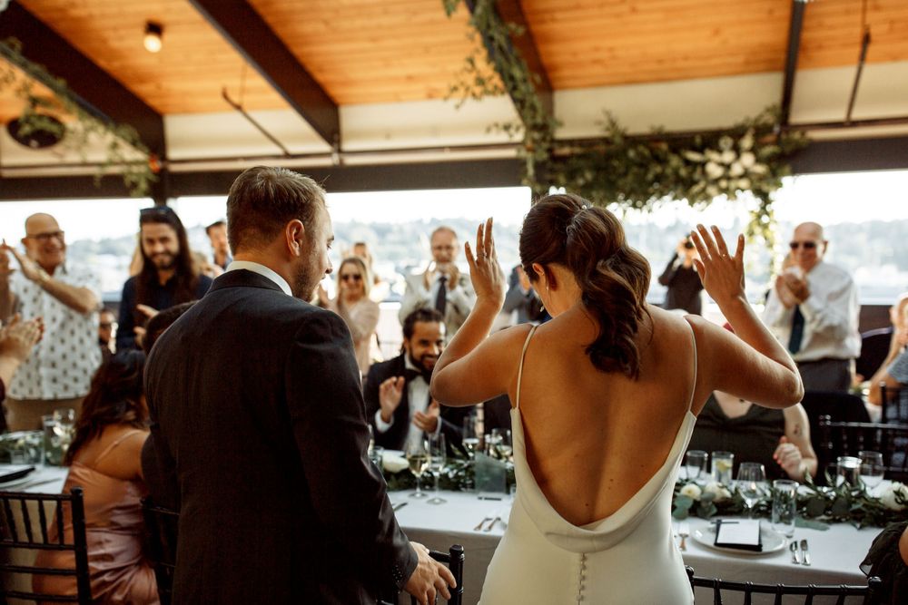 Elegant wedding couple sharing a joyful moment at their reception venue with exposed wood beams.