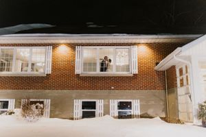 Illuminated brick house exterior on a snowy winter night.