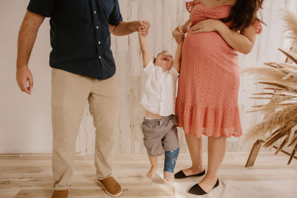 A family shares a tender moment together as they dance in a bright room with pampas grass decor.