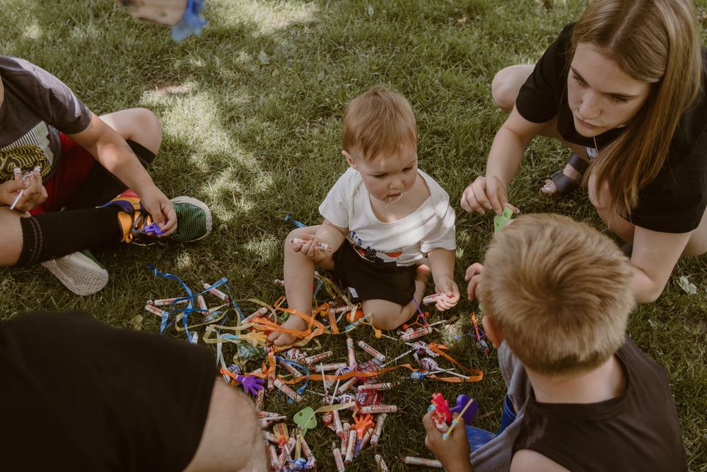 Kids gather around scattered candy and prizes on the grass during an outdoor party.