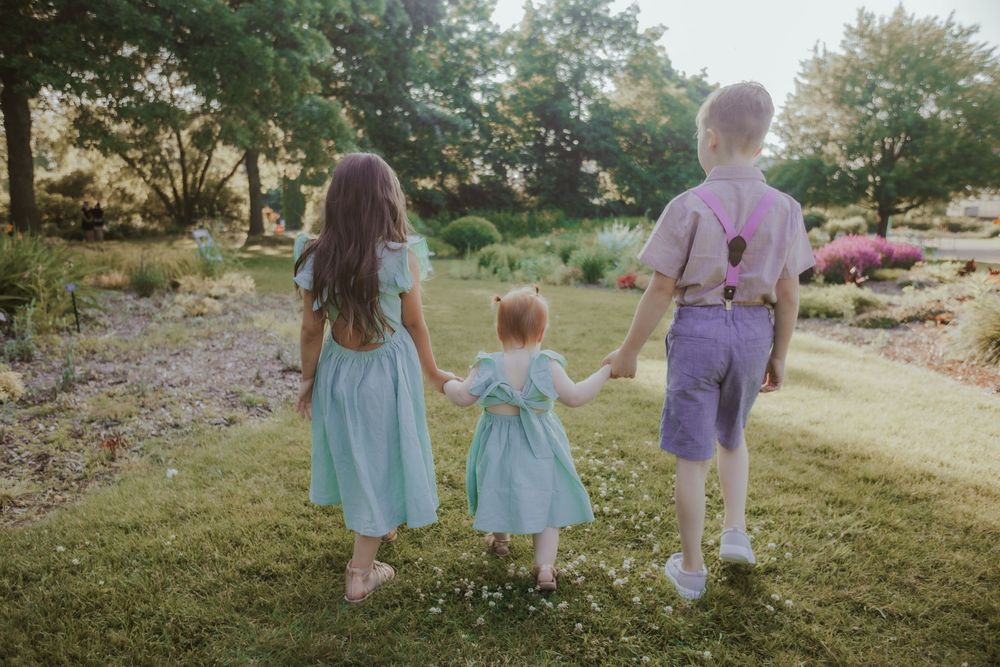 Family walking together on grassy path through park at golden hour sunset.