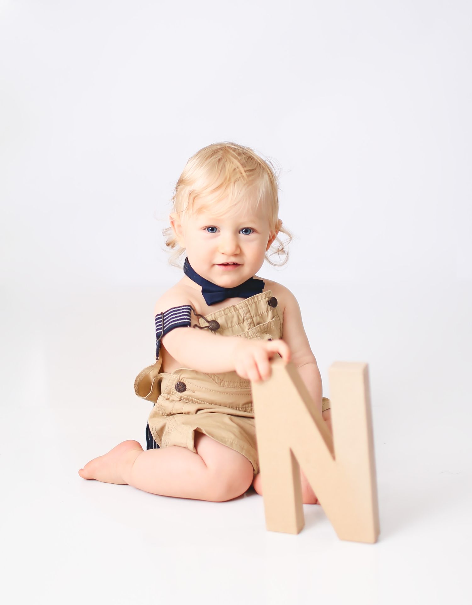 Baby boy holding cardboard letters to spell ONE