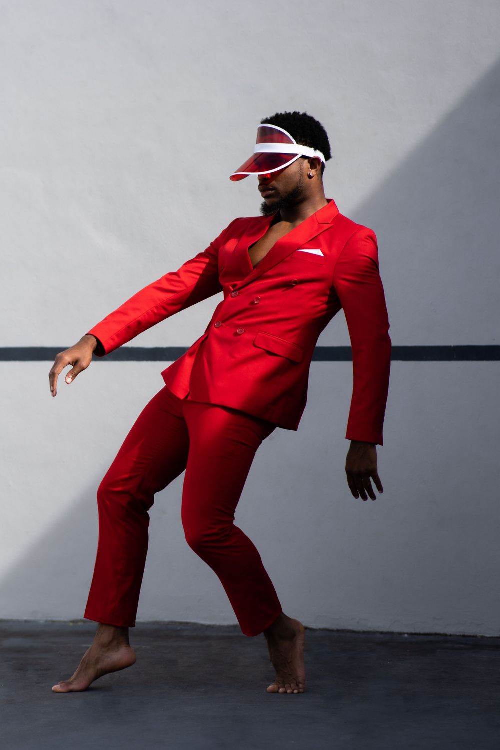 Artistic dance movement captured in crisp red suit against minimalist studio setting.