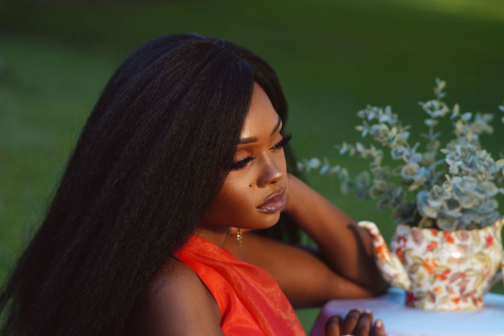 Artistic outdoor portrait with orange dress and decorative potted flowers.