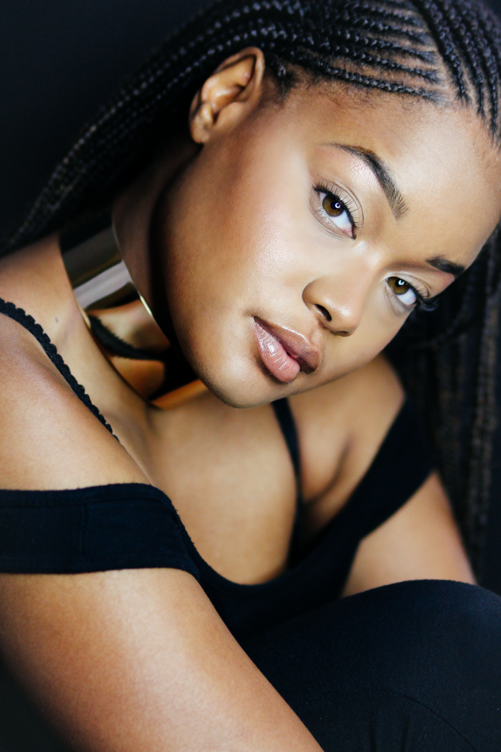 Close-up beauty portrait with braided hairstyle and gold statement earring.