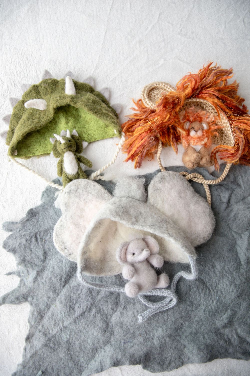 Three felt animal-themed bags featuring a dinosaur, lion, and elephant with small plush toys.