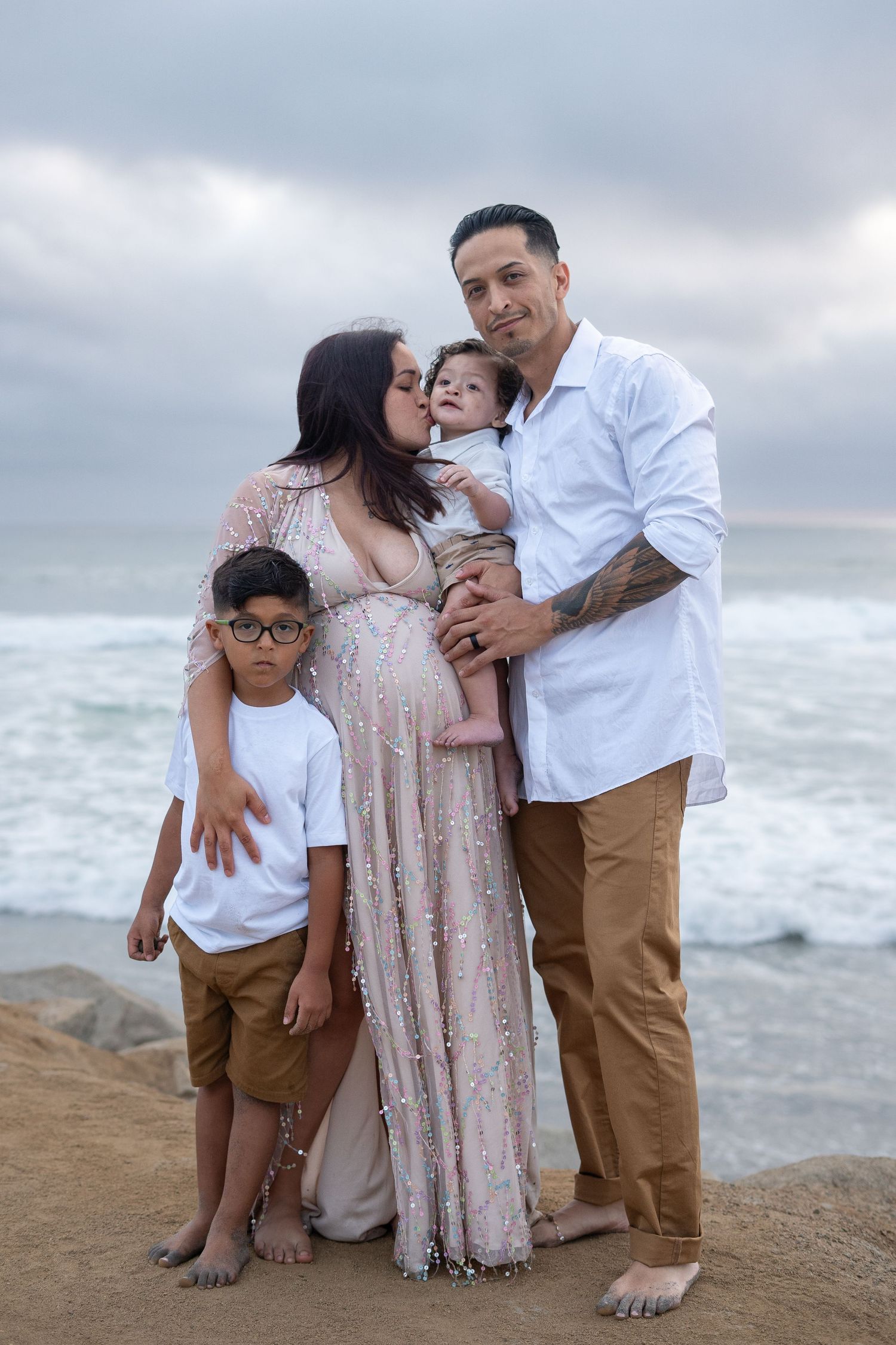 Family beach portrait sequence with waves and cloudy sky backdrop.