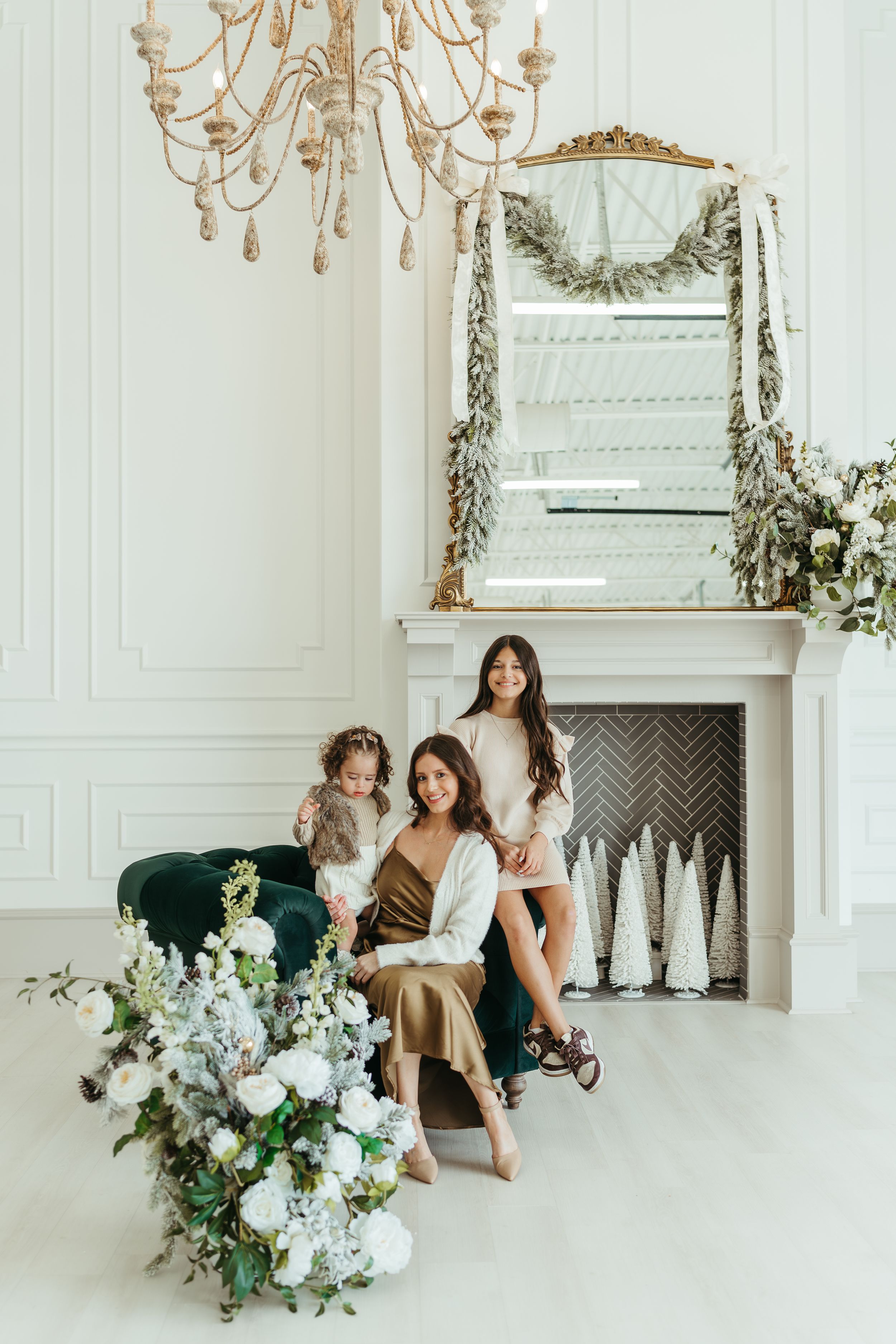 Elegant white room with chandelier and fireplace decorated with floral arrangements for photo session.