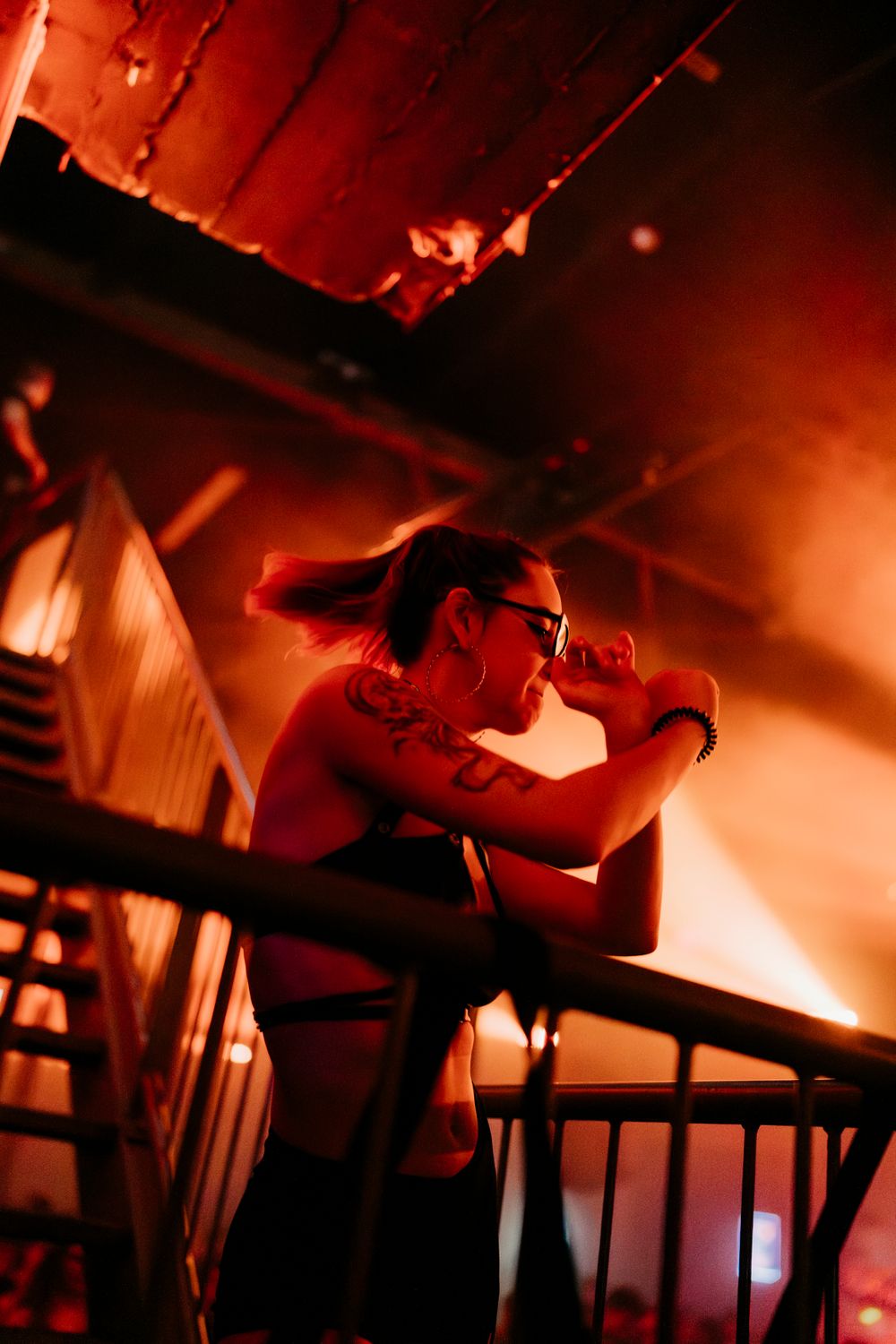 DJ performing in dramatic red lighting at a nightclub event.
